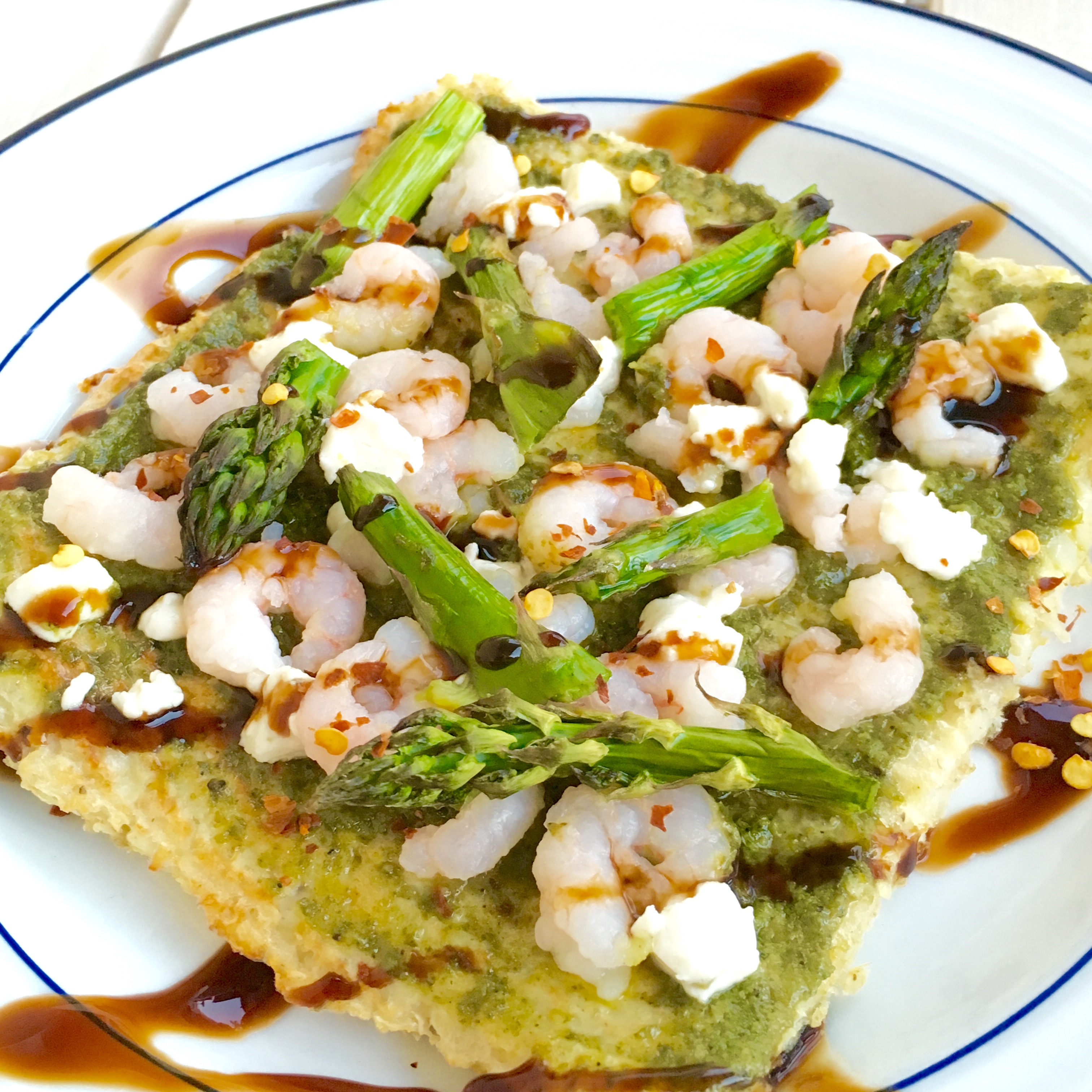 Walnut pesto and shrimp with asparagus on this gluten-free, dairy-free cauliflower crust is the perfect light bite for spring!